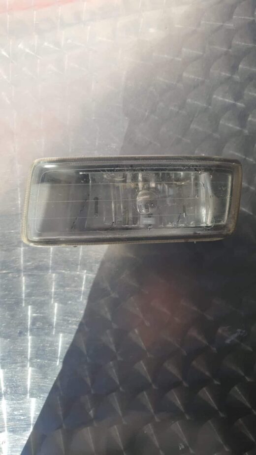 Front angled view of a mounted spotlight on a vehicle roof, showing grille and light lens details.Front angled