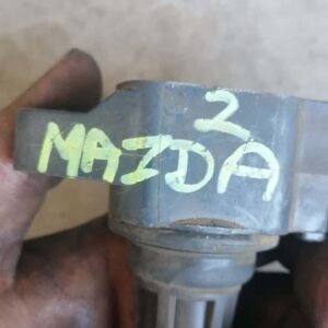 Close-up of a black Mazda 2 pencil coil positioned upright on a plain surface, new condition.Close-up of a bla