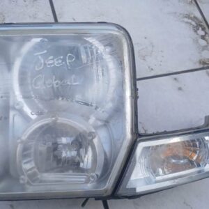 Left front headlight of a Jeep Cherokee shown from an angled front view against a plain background.Left front