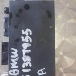 Close-up of a rectangular black BMW E36 control module viewed front-facing on a white background.Close-up of a
