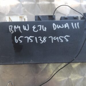 Front-angle view of BMW control unit for alarm system, showing connector pins and black casing.Front-angle vie