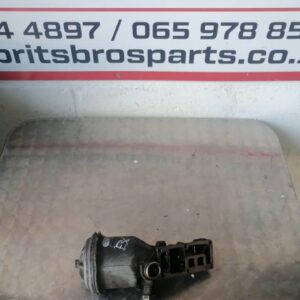Front view of a clean BMW E36 318 oil filter housing showing mounting points and oil passage openings.Front vi