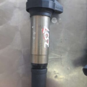 Used ignition coil for Peugeot 207 shown from a side angle on a gray surface.Used ignition coil for Peugeot 20