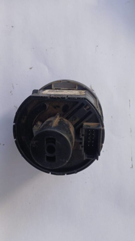 Close-up front view of a VW Polo headlight switch showing control knob and mounting tabs.Close-up front view o