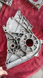 Close-up of a grey automotive timing belt cover viewed from the front, showing mounting points clearly.Close-u