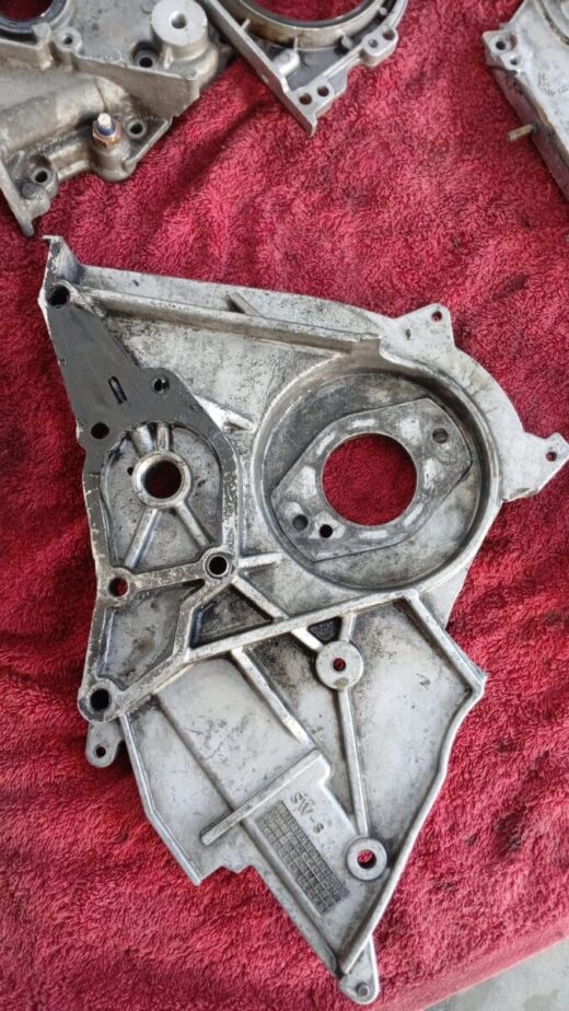 Close-up front angle of a grey automotive timing belt cover for a Hyundai H100, showing mounting holes and ope