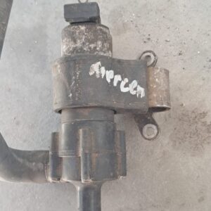 Close-up of a used Mercedes engine heater valve showing inlet and outlet ports and mounting bracket.Close-up o