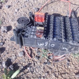 Close-up of a used Mercedes W210 fuse box showing top and side connectors against a white backgroundClose-up o
