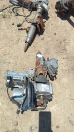 Used electric steering column for Mazda 2, shown from a top angle with wiring and mounting points visible.Used