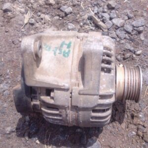 Front view of a used alternator for a small car engine, showing the pulley side and mounting points.Front view