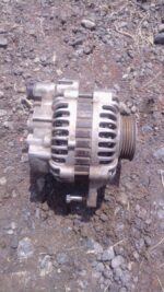 Front view of a used alternator for a Mitsubishi Colt showing mounting points and pulley.Front view of a used