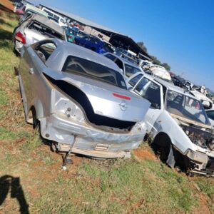 Front and side view of a stripped silver hatchback car with missing parts, showing body shell and wheels.Front