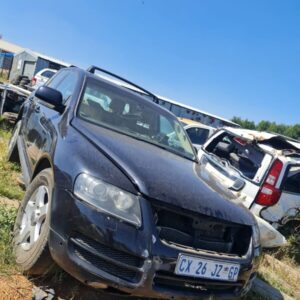 Front view of a used Volkswagen SUV stripped for spares with hood open and missing parts.Front view of a used