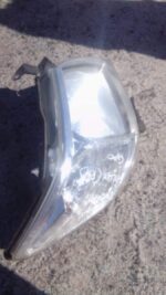 Right front vehicle headlight assembly angled to show lens and mounting points, used condition.Right front veh