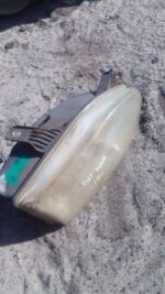 Right headlight for Fiat Sienna, front angle view, used condition, showing lens and mounting points.Right head