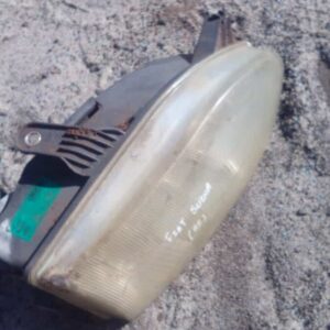 Right headlight for Fiat Sienna, front angle view, used condition, showing lens and mounting points.Right head