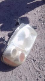 Right-side NP300 truck headlight assembly shown front-facing, used condition with visible wiring and mounting