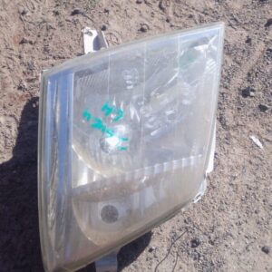 Front view of a used left headlight for an Isuzu KB, showing clear lens and mounting bracket details.Front vie