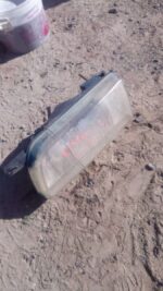 Front left side view of a used Nissan Sentra headlight assembly showing lens and mounting points.Front left si