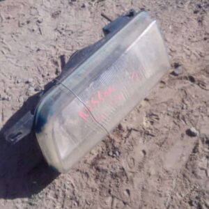 Front left side view of a used Nissan Sentra headlight assembly showing lens and mounting points.Front left si