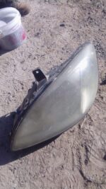 Front angle of a used left headlight for a 2002 Mercedes Benz Vito showing clear lens and connector detailsFro