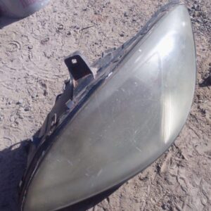 Front angle of a used left headlight for a 2002 Mercedes Benz Vito showing clear lens and connector detailsFro