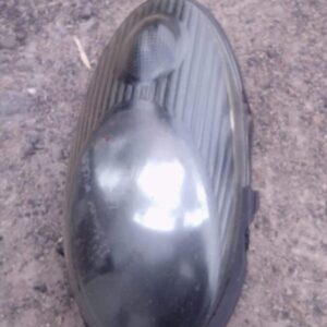 Used left headlight assembly for a 2007 Nissan Micra, angled left side view, clean with minor wear.Used left h