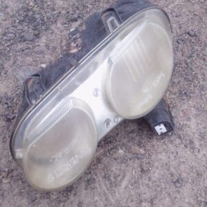 Left side car headlight assembly shown from front angle, used condition visible with slight wear.Left side car