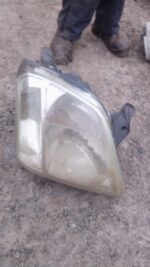 Used right headlight for Isuzu KB shown from front angle, highlighting headlamp lens and casing.Used right hea