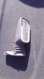 Left side mirror for Fiat Uno, shown from front angle, used condition with slight wear visible.Left side mirro