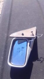 Left side exterior mirror for BMW E36, shown from front angle, used condition with mounting bracket visible.Le