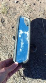 Rear view mirror for BMW E36, shown from front angle, used condition with intact mounting bracket.Rear view mi