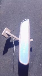 Rear view mirror for Mazda 323 shown from front angle, used condition evident with minor wear.Rear view mirror