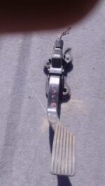 Used accelerator pedal for 2010 Dodge Caliber shown from side angle on white background.Used accelerator pedal