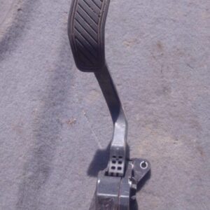 Close-up of a used accelerator pedal positioned upright against a plain background.Close-up of a used accelera