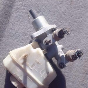 Used brake master cylinder shown from a side angle with connected reservoirs and mounting points.Used brake ma