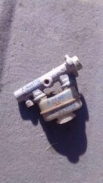 Front-left angled view of a used brake master cylinder assembly with attached reservoir and connectors.Front-l