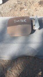 Used fuel flap for Renault Duster shown from a front side angle on a white surface, with minor wear visible.Us