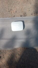 Used Hyundai Accent fuel flap shown front-side view with mounting points visible against white background.Used