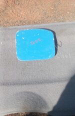 Front view of a used fuel flap for a compact hatchback, showing exterior surface and hinge mechanism.Front vie
