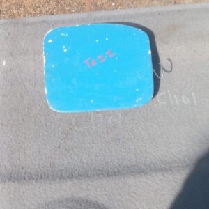 Front view of a used fuel flap for a compact hatchback, showing exterior surface and hinge mechanism.Front vie