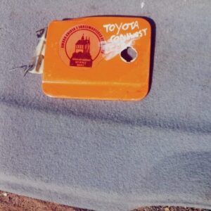 Front view of a used fuel flap for Toyota Conquest, showing mounting points and latch mechanism.Front view of