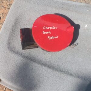 Used fuel flap for a 1996 Chrysler Neon, shown from the front angled view.Used fuel flap for a 1996 Chrysler N
