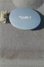 Used fuel flap for Mazda 3, shown flat against white background with slight shadow from top angle.Used fuel fl