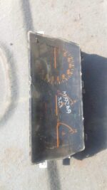 Front view of a used Mazda 323 instrument cluster showing speedometer, tachometer, and gauges.Front view of a