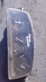 Front view of a used Honda car instrument cluster with speedometer and indicators visible.Front view of a used