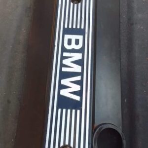 Top-down view of a used black BMW E46 engine cover with silver accents and visible mounting points.Top-down vi