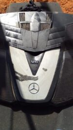 Used V6 engine cover viewed from top front angle, showing mounting points and Mercedes emblem.Used V6 engine c