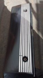 Top-down view of a used black E39 engine cover with BMW logo and central circular intake opening.Top-down view