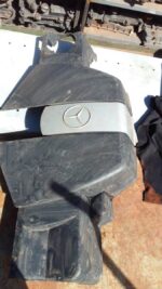 Top-down view of a used black engine cover designed for Mercedes W203, showing mounting points and surface det